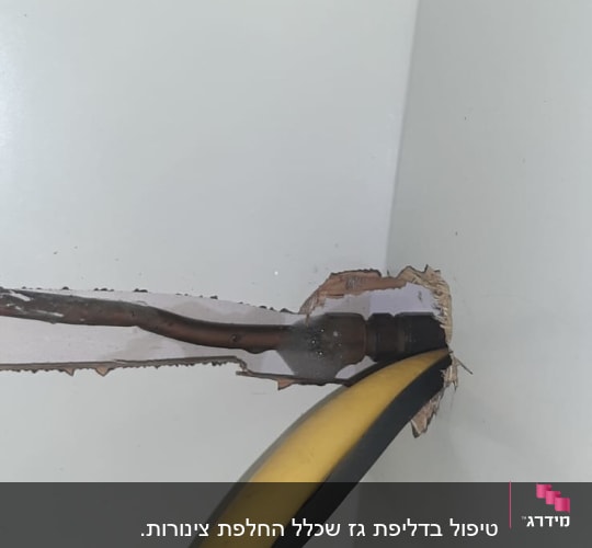 צינור גז צהוב ושחור יוצא מקיר לבן